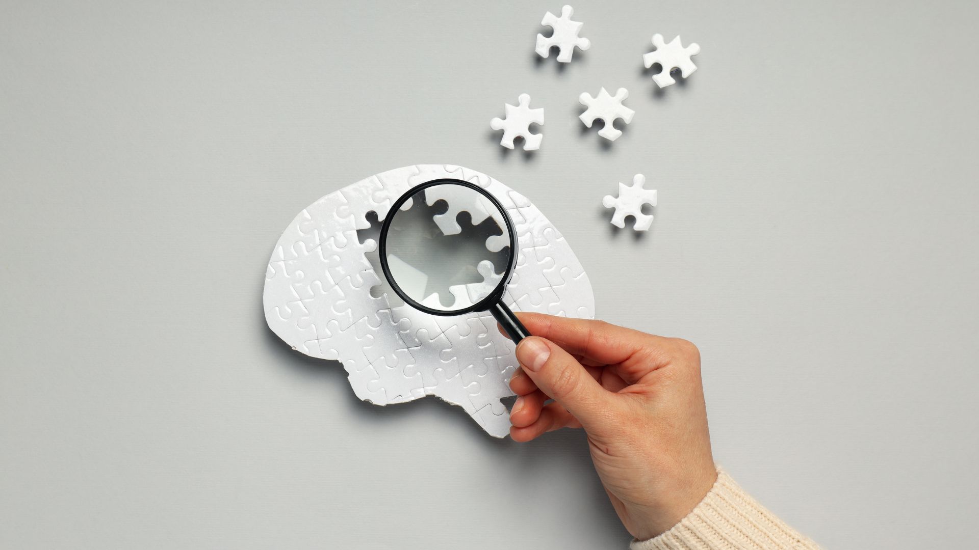 hand with magnifying glass over puzzle 